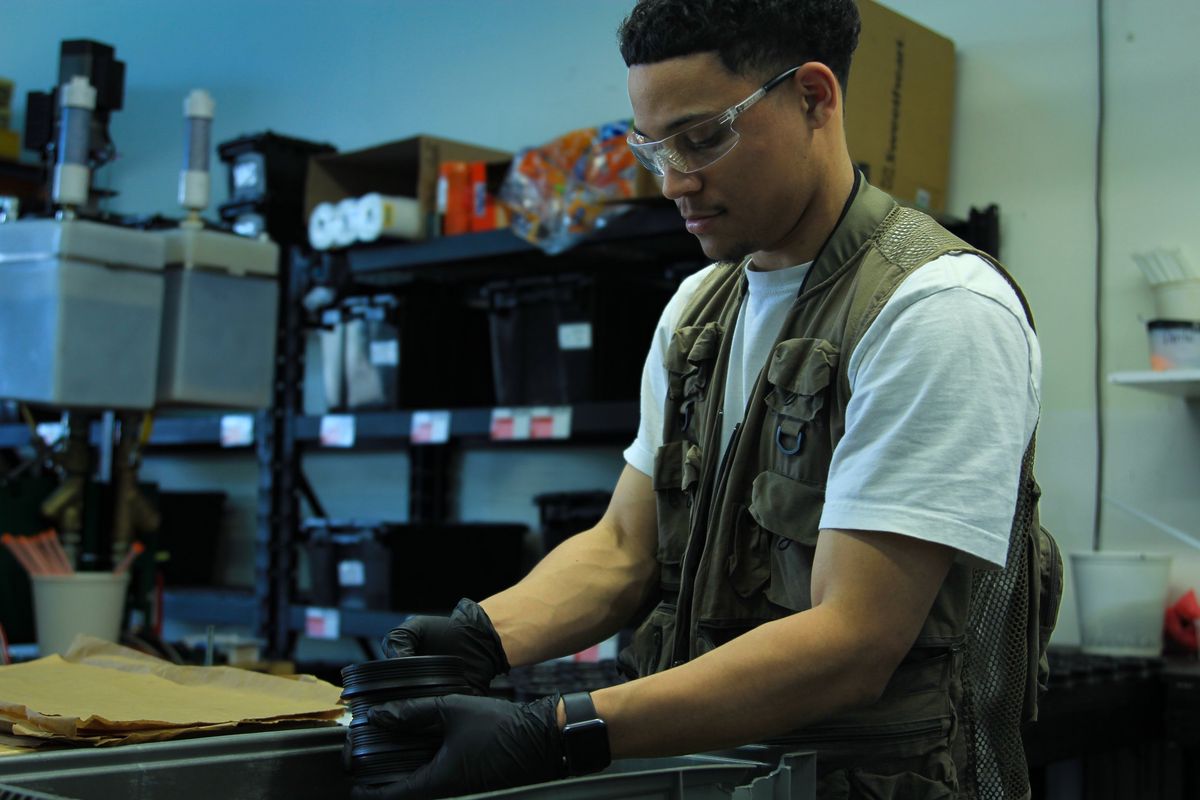 Technician in safety glasses and nitrile gloves removing a cured polyurethane part from its mold