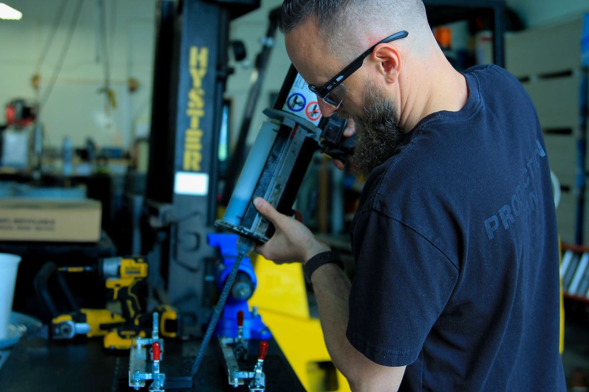 Operator dispensing mixed polyurethane from a handheld two-part cartridge gun at a bench